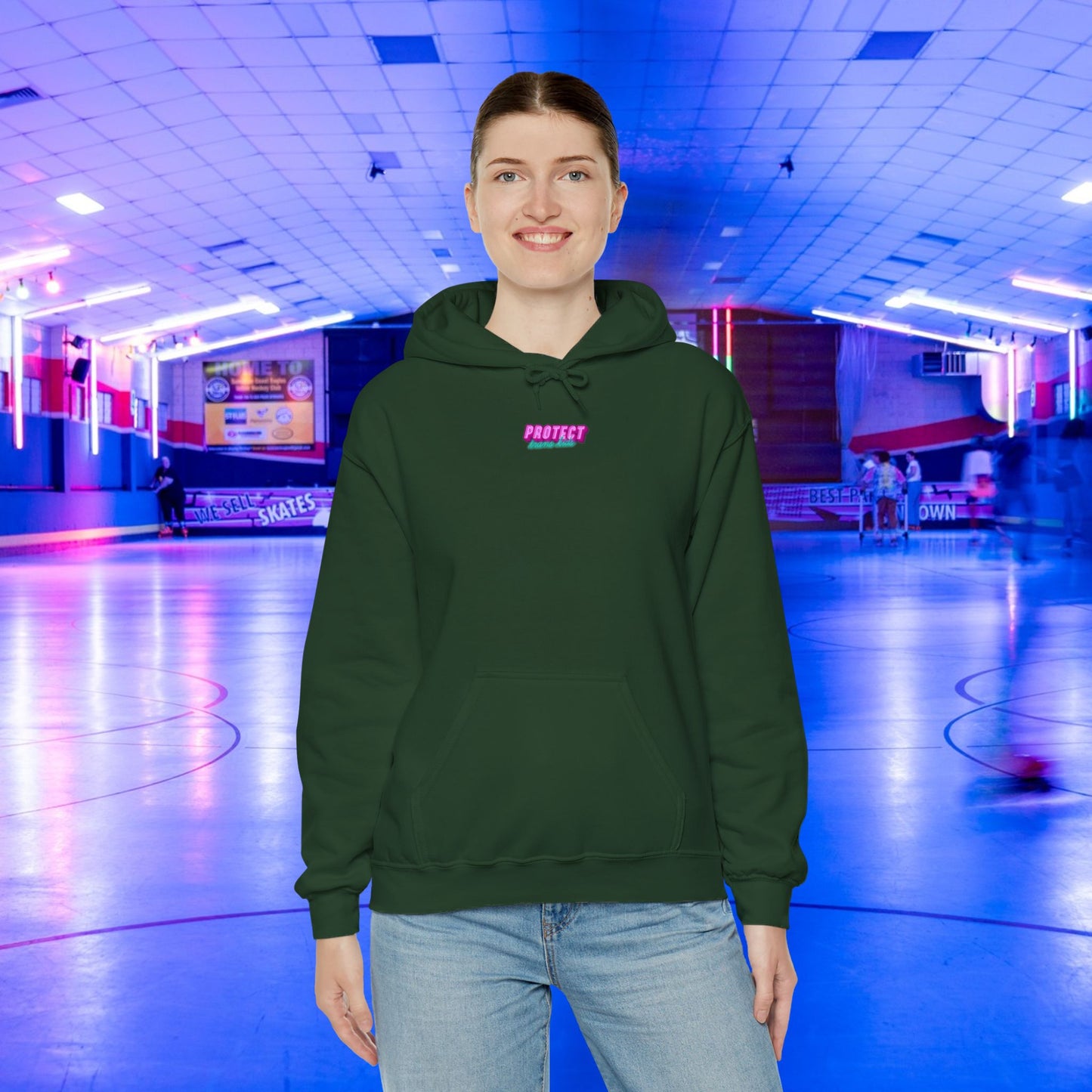 Sporting a Protect Trans Kids Hoodie - Australian Shipping in dark green, someone stands at a roller rink illuminated by blue and pink neon lights. Blurred skaters span the spacious floor, all captured under the charm of sustainably grown cotton.
.