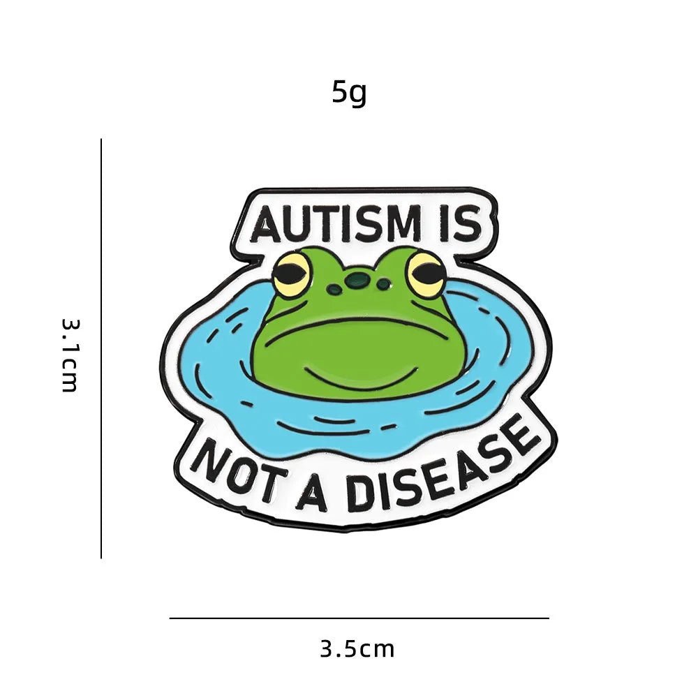 Enamel pin with a frog design and text 'Autism is not a disease' with measurements on a white background.