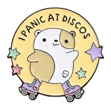 This adorable enamel pin from Gay Skate features a cute cartoon hamster wearing roller skates and a small skull on its side, set against a yellow circle background adorned with colorful stars. It's the perfect accessory for adding charm to any outfit. The text above the design reads, "I Panic At Discos.