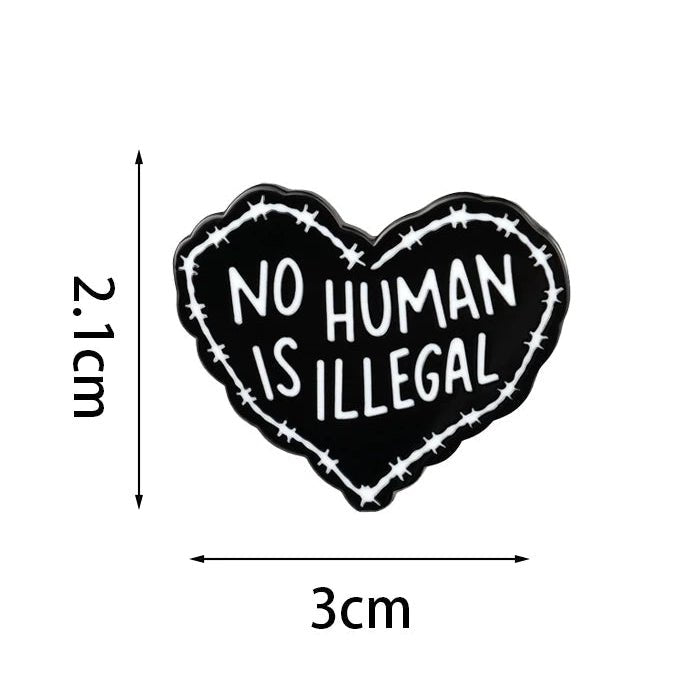 Heart-shaped badge with 'No Human Is Illegal' text and barbed wire design