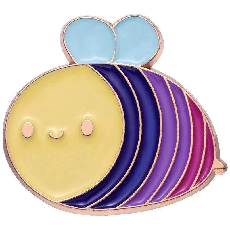 A cute, cartoon-style bee enamel pin with a yellow face, light blue wings, and purple-striped body celebrates LGBTQ+ Pride. Part of the Pride Flag Fist enamel pins collection: Ace, Bi, Pan, Lesbian, Rainbow, and Trans.