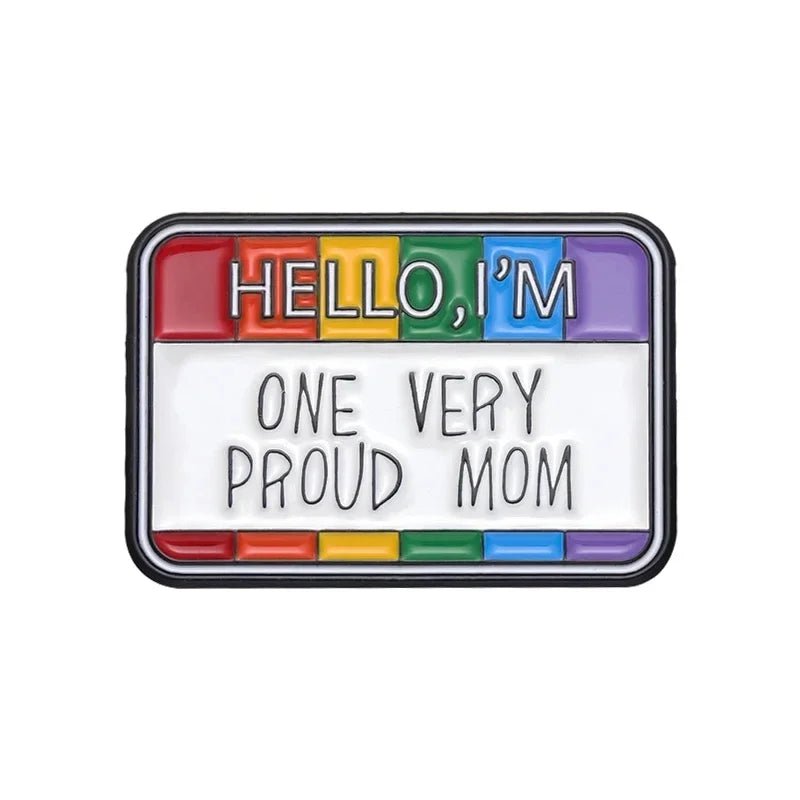 A rectangular enamel pin with a rainbow border, inspired by the LGBTQ+ Pride flag, featuring "HELLO, I'M ONE VERY PROUD MOM" in bold on white. From our Pride Flag Fist enamel pins: Ace, Bi, Pan, Lesbian, Rainbow, and Trans designs.