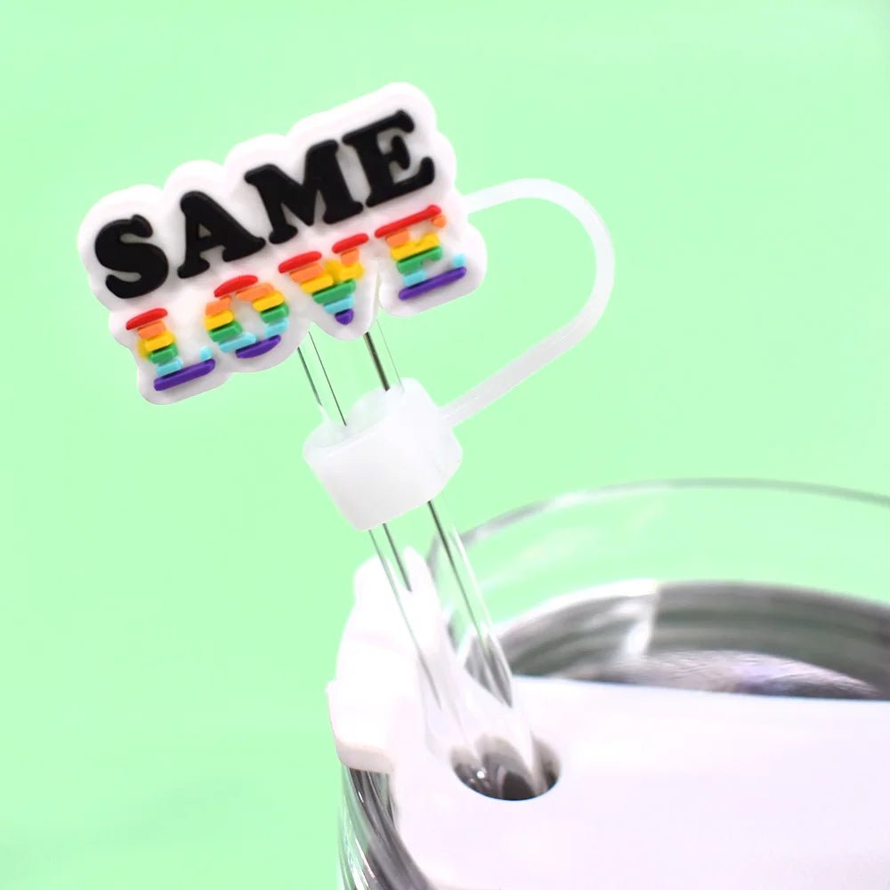 Close-up of a tumbler lid with a clear straw and the Pride straw topper, which fits Stanley Cup straws. The Rainbow Pride topper features a tag reading "SAME LOVE" in colorful letters against a light green background, enhancing its vibrant pride designs.