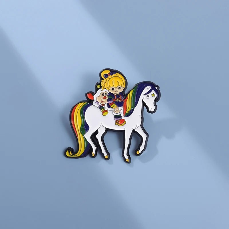 The Rainbow Brite Horse - Enamel Pin features a blonde girl and her white companion riding a white horse with a rainbow mane and tail on a light blue background—perfect for pride accessories lovers.