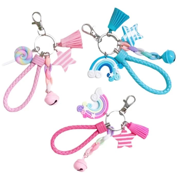 Three vibrant Rainbow Key Chains from Gay Skate come with braided loops and whimsical charms, featuring stars, rainbows, tassels, and bells. These kawaii pastel accessories include pink and blue accents in their design, making them an ideal choice for pride wear.