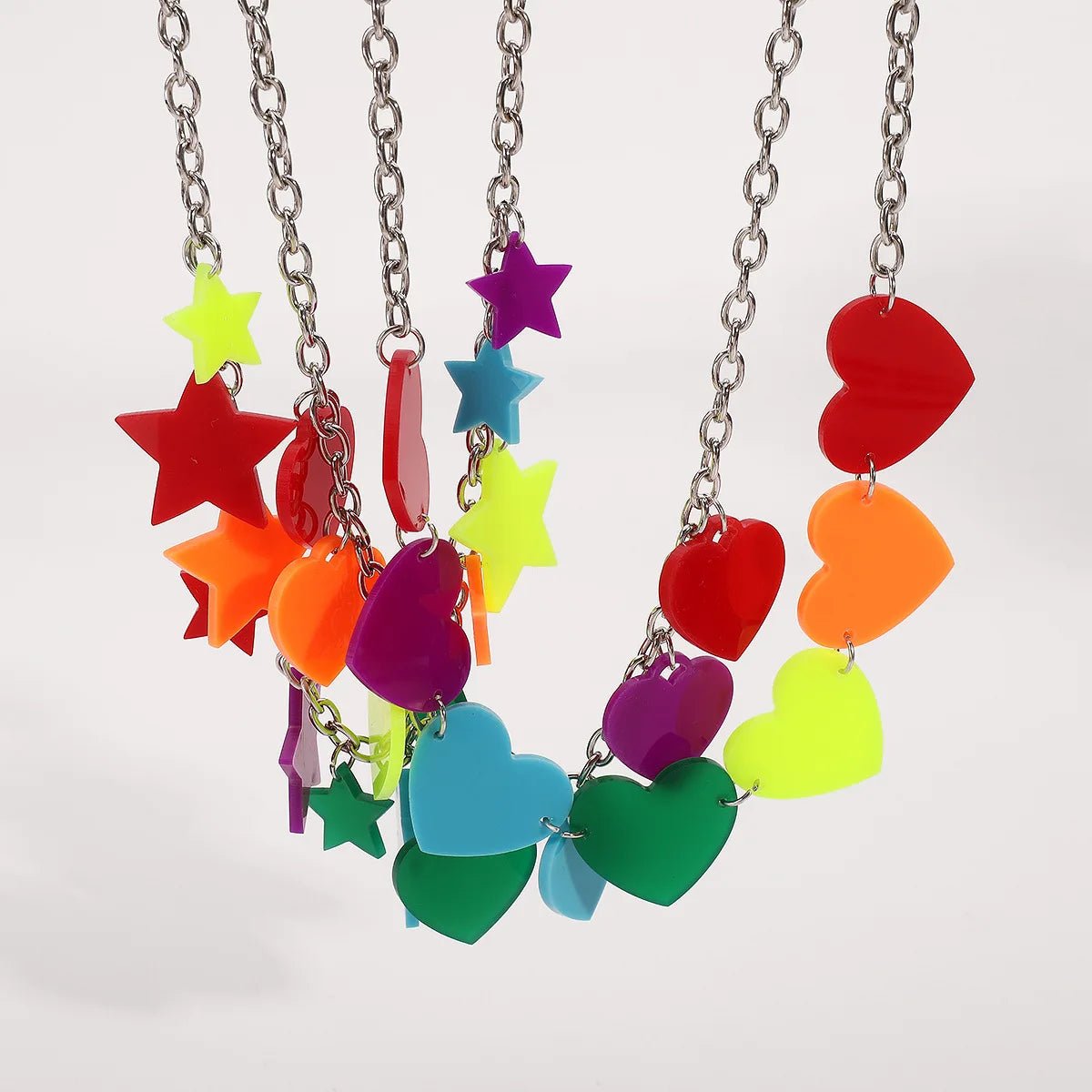 The Rainbow Pride Acrylic Necklace features three designs with large, colorful acrylic hearts, stars, and geometric shapes on silver chains—available in red, yellow, green, blue, orange, and purple. Perfect for pride celebrations.