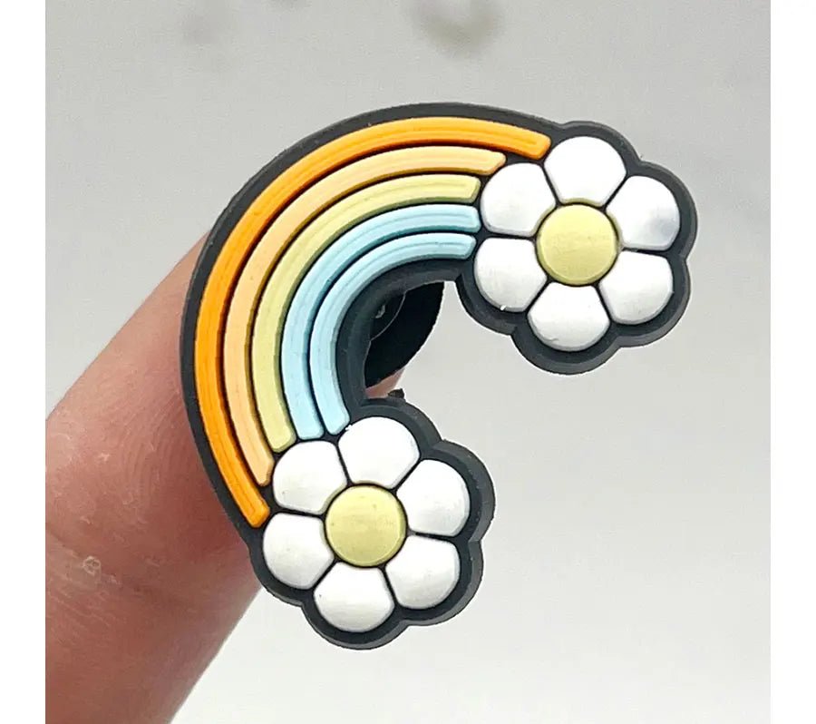This Retro Roller Skate theme Shoe Charm features a cartoon rainbow with orange, yellow, and blue stripes ending in white flowers with sunny centers. It resembles an orange jibbitz perfect for adorning your favorite quad skates, held artfully between fingers against a plain backdrop.