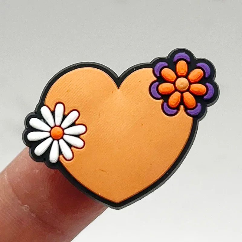 The heart-shaped Retro Roller Skate theme Shoe Charm features an orange surface with a purple and orange flower at the top right and a white one at the bottom left, set against a neutral background, exuding vintage charm.