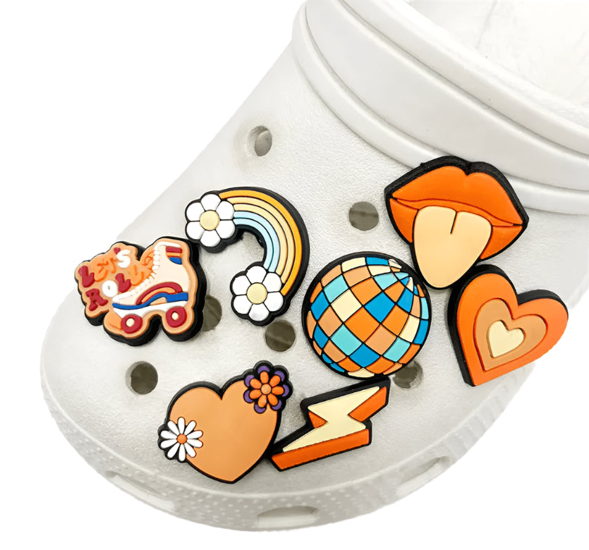 The Retro Roller Skate theme Shoe Charms, vintage-inspired in white, sport vibrant orange jibbitz like a quad skate, rainbow, disco ball, playful lips with tongue out, a heart with flowers, and a striking lightning bolt—all in lively multicolored designs.