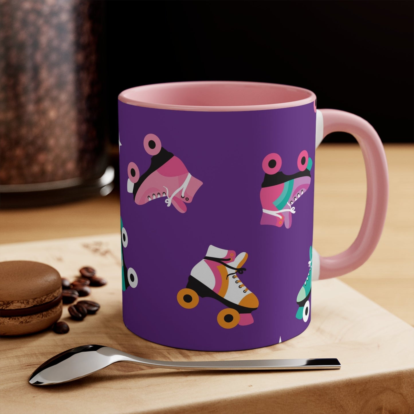 The Printify Roller Skates with a purple background - cute colourful accent mug features a white ceramic coffee mug with a pink handle and interior. Its design is adorned with various colorful roller skate illustrations against a vibrant purple background, showcasing skates in different styles and colors for a playful touch.