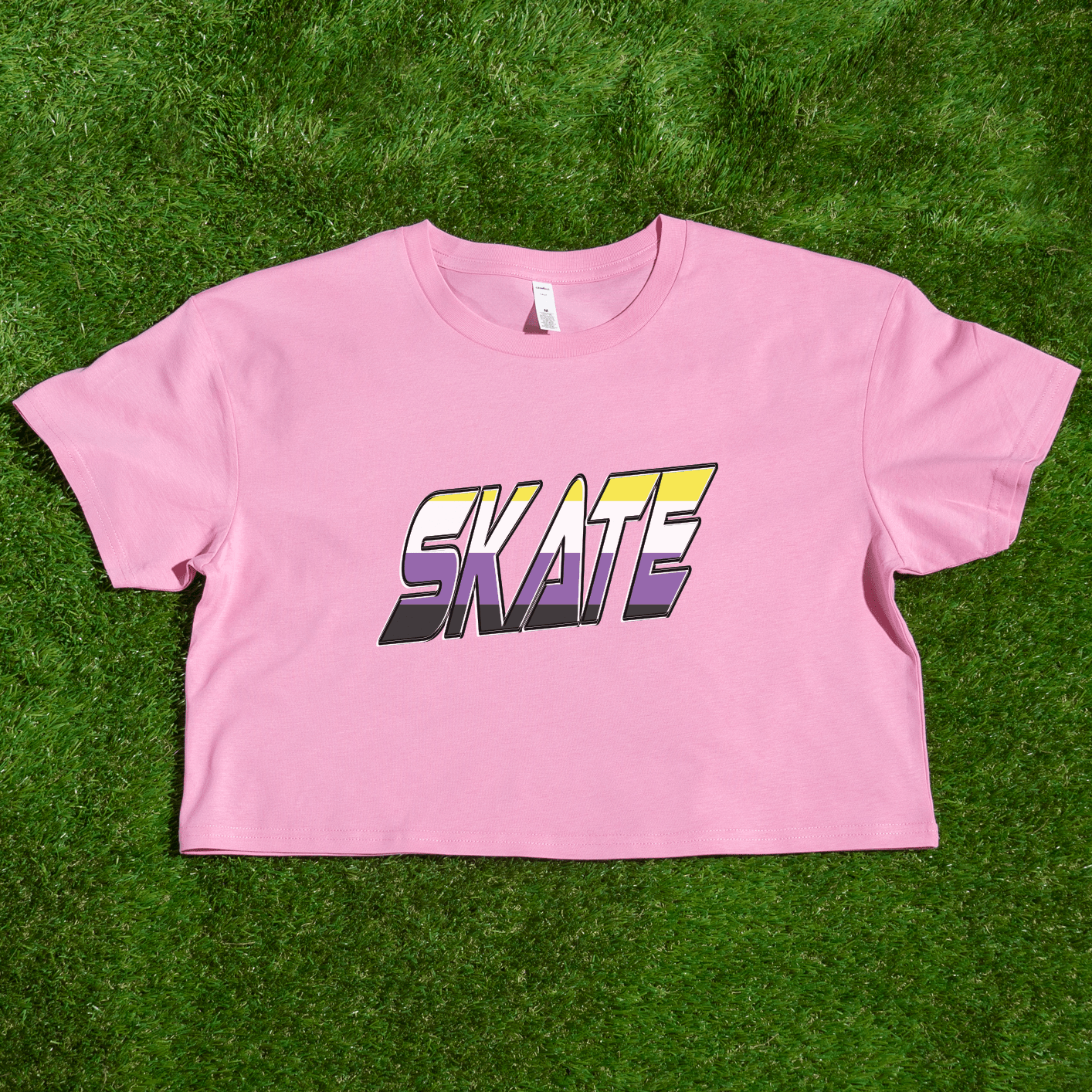 A black crop top with short sleeves from Gay Skate, featuring the word "SKATE" in bold, gradient letters across the front. The gradient transitions from yellow at the top to purple at the bottom, providing a vibrant and stylish look that proudly embraces non-binary skate culture. This unique tee is locally printed and known as the SKATE non-binary pride flag crop tee.
