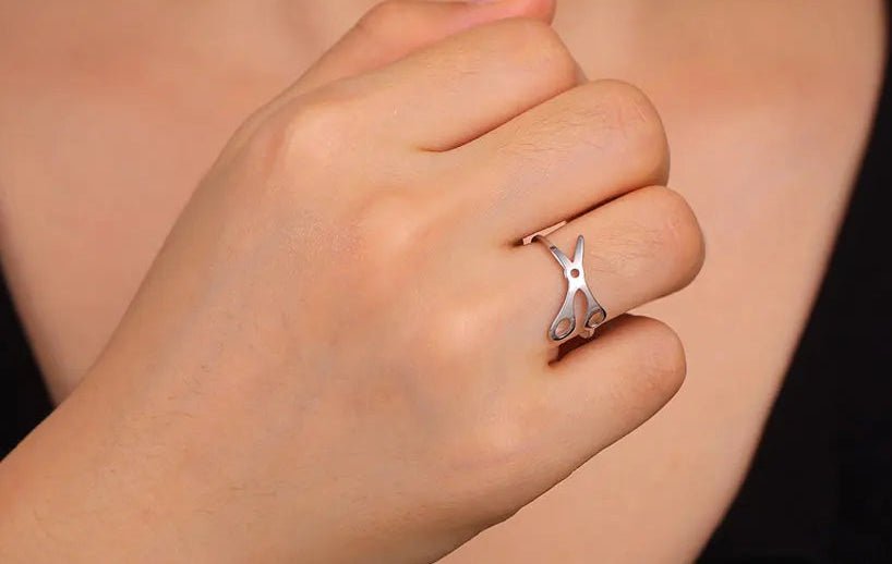 A hand wearing the Stainless Steel or Gold Scissor Ring celebrating Sapphic, WLW, and Lesbian Pride, shaped like scissors, against a plain background with a black top visible.