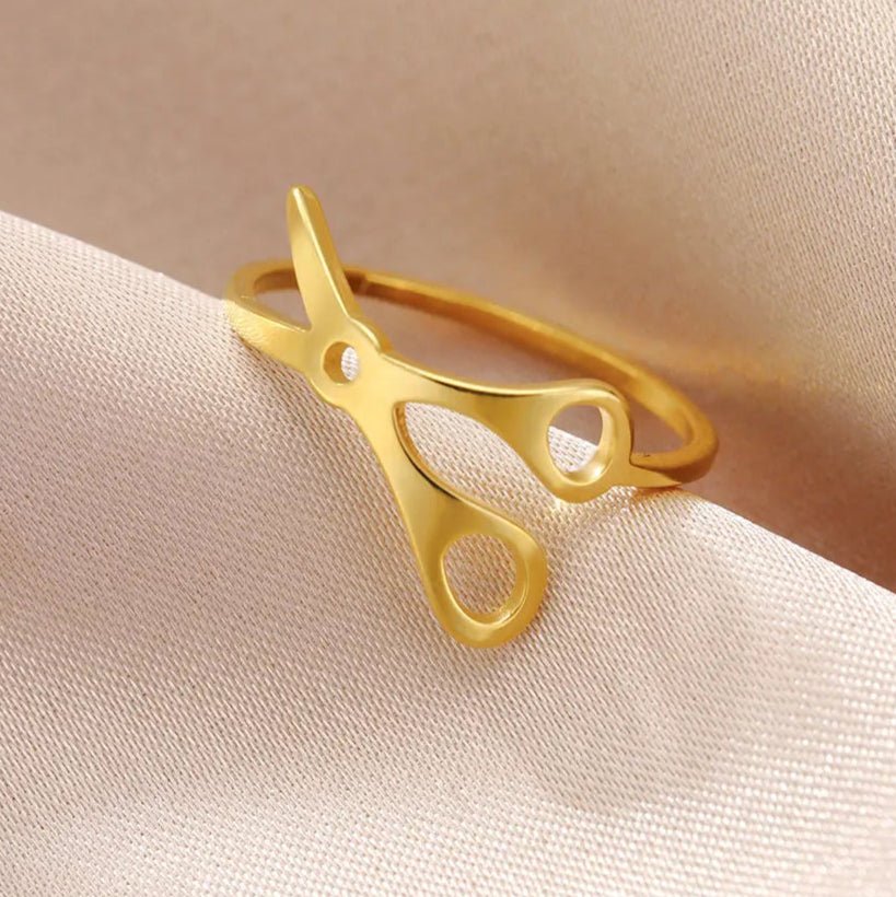A Stainless Steel or Gold Scissor Ring for Sapphic, WLW and Lesbian Pride rests on soft, light pink fabric, with a "Cute Scissors Ring" label at the top—a charming accessory for anyone celebrating sapphic pride.