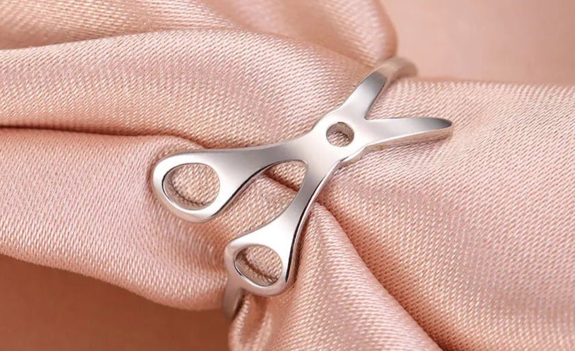 The Stainless Steel or Gold Scissor Ring—Sapphic, WLW and Lesbian Pride—is displayed on soft light pink satin, featuring detailed handles and blades for a unique accessory that celebrates queer pride.