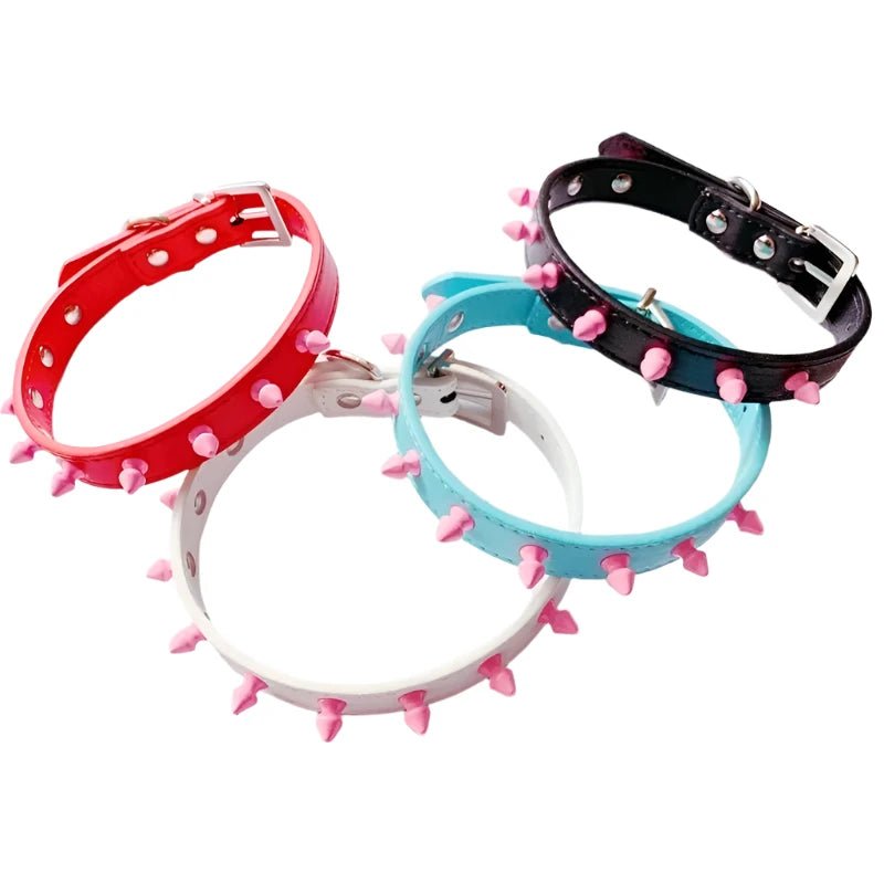 Four Studded Pastel Choker Collars from Gay Skate in red, black, white, and blue hues are beautifully arranged. Each collar features pink spikes and silver buckles, resembling a kawaii choker design and creatively overlaps in a circular pattern.