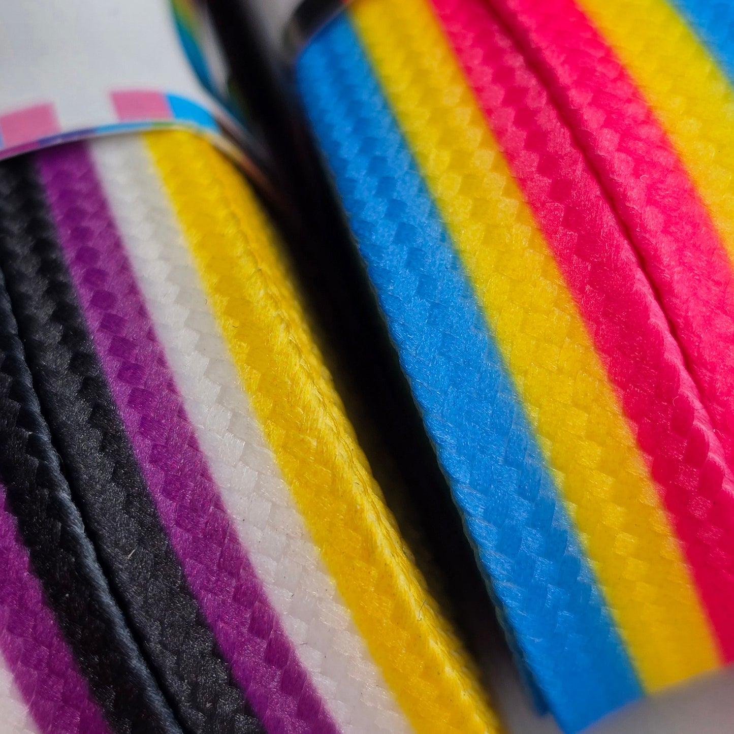 Close-up of Waxed Skate Laces featuring textured, durable ribbons with colorful stripes representing Trans, Rainbow, Non-Binary, Pansexual, Bisexual, and Lesbian pride flags in a vibrant diagonal pattern.