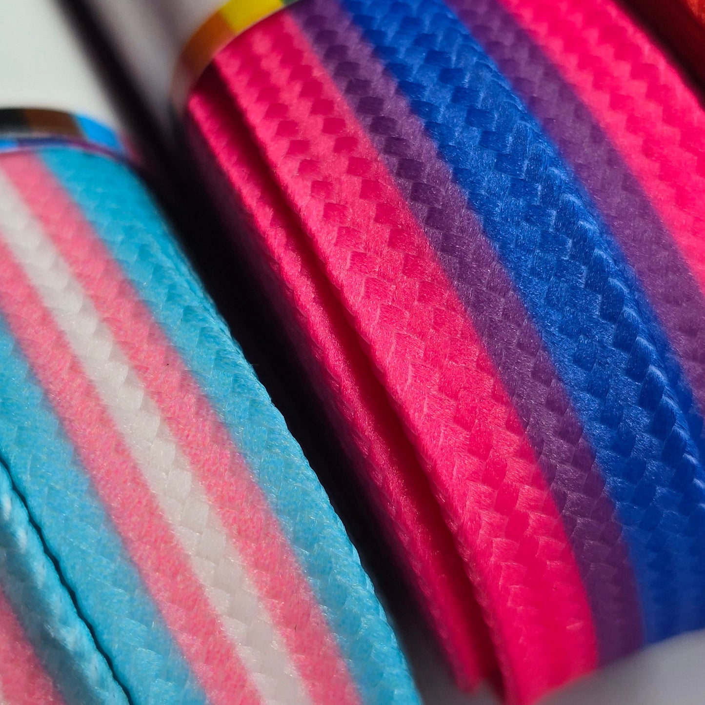 Close-up of Waxed Skate Laces featuring textured, patterned fibers in pride flag colors—Trans, Rainbow, Non-Binary, Pansexual, Bisexual & Lesbian. Arranged side by side, they have a slightly shiny finish and are made for durability.