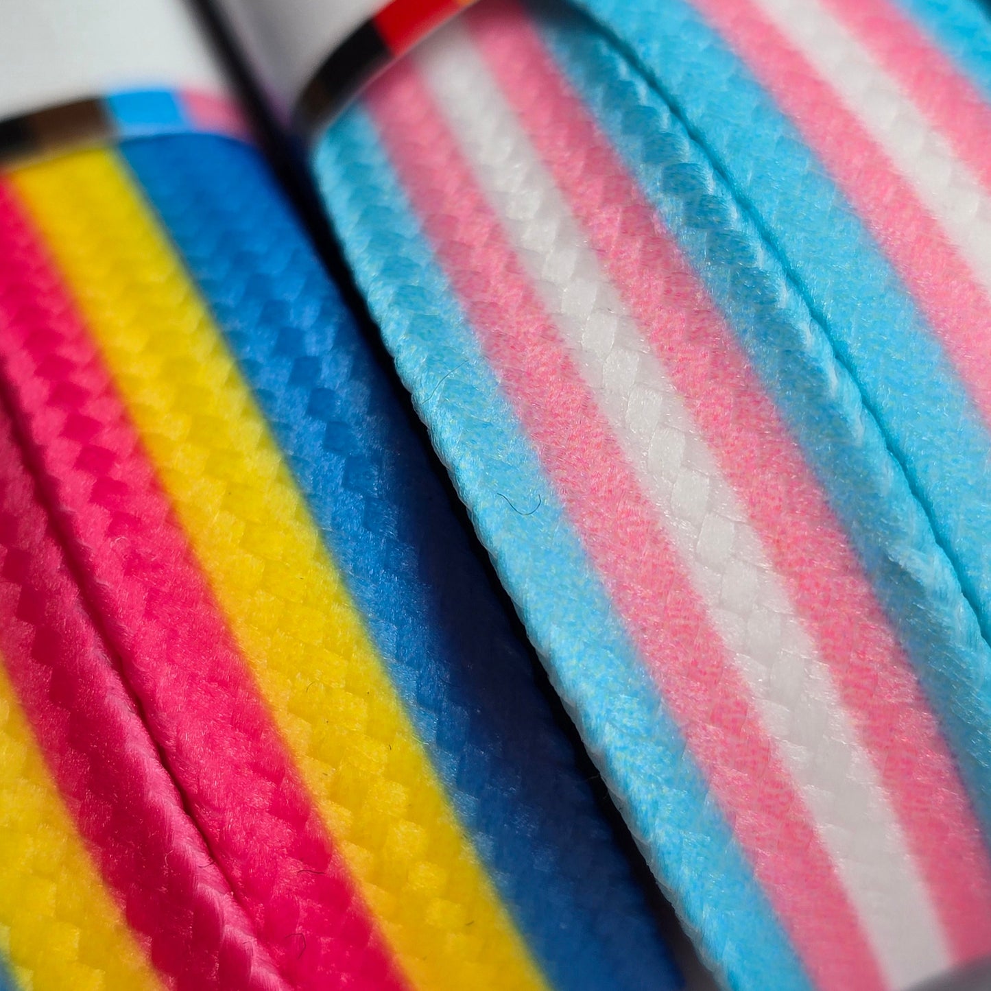 Close-up of Waxed Skate Laces in pride flag colors—one with pink, yellow, and blue for pansexual pride, and another with pink, blue, and white for transgender pride—showcasing their vibrant woven texture and durable build.