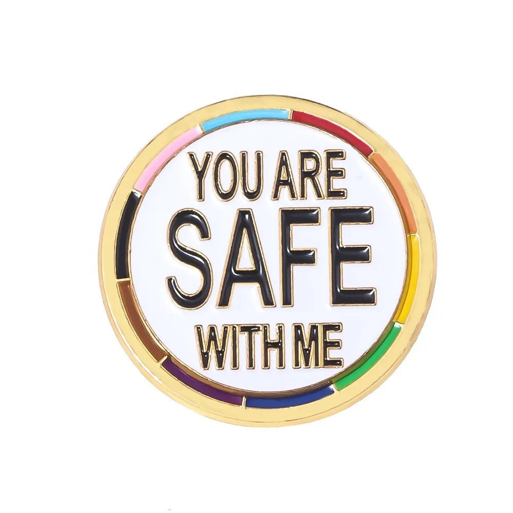 The "You Are Safe With Me - progress pride and gold round pin" features a vibrant gold border, rainbow accents, and bold black text on white center. A perfect addition to your pride accessories collection.