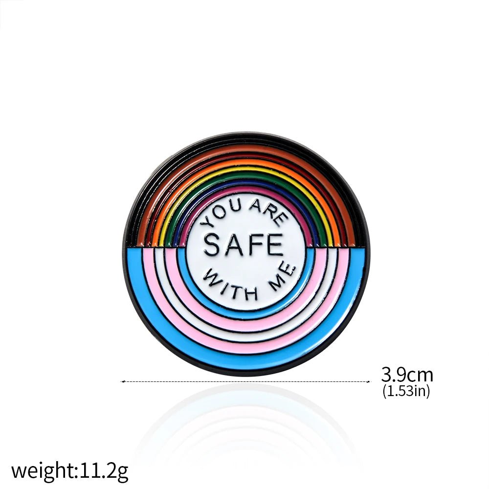 The "You Are Safe With Me" enamel pin features rainbow and pastel stripes with the message "YOU ARE SAFE WITH ME." It measures 3.9 cm in diameter, weighs 11.2 g, and pairs perfectly with pride key rings or other ally badges.