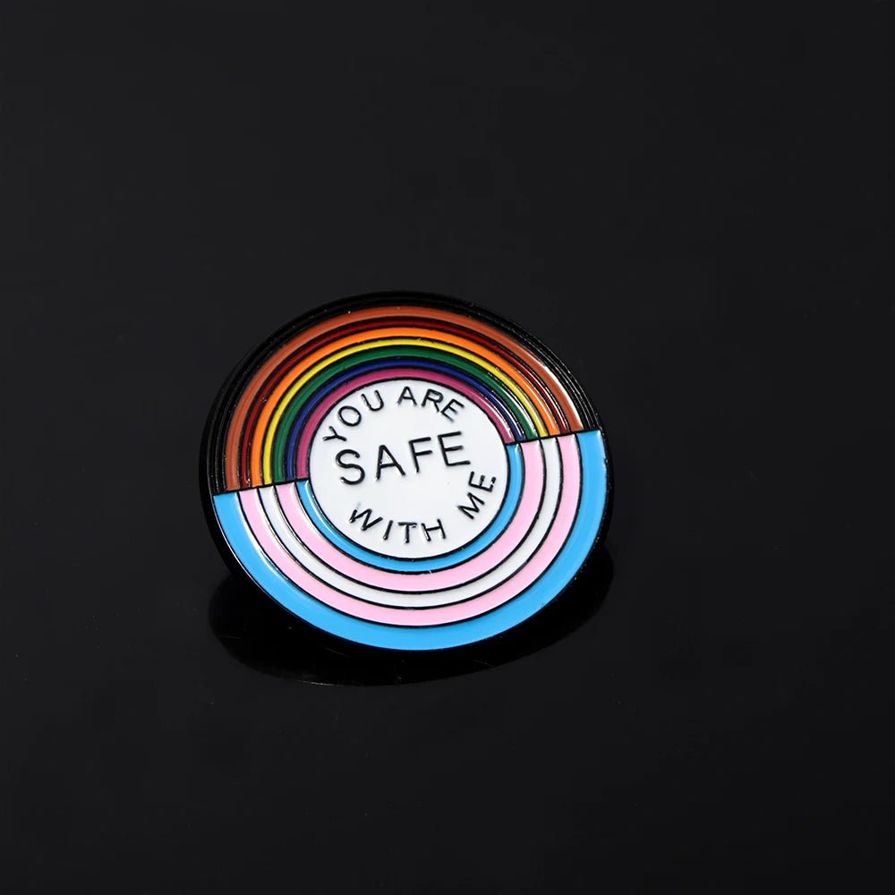 The "You Are Safe With Me" enamel pin features rainbow and trans pride stripes with the message in the center, making it a perfect pride accessory from our ally badges and key rings collection.