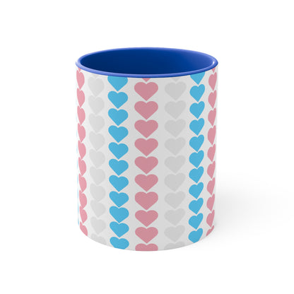 The Trans pride flag love hearts colourful accent mug by Printify features a white exterior adorned with vertical rows of pink, blue, and white hearts, reminiscent of the trans pride flag. Its cheerful and colorful appearance is enhanced by the pink handle and inner rim.