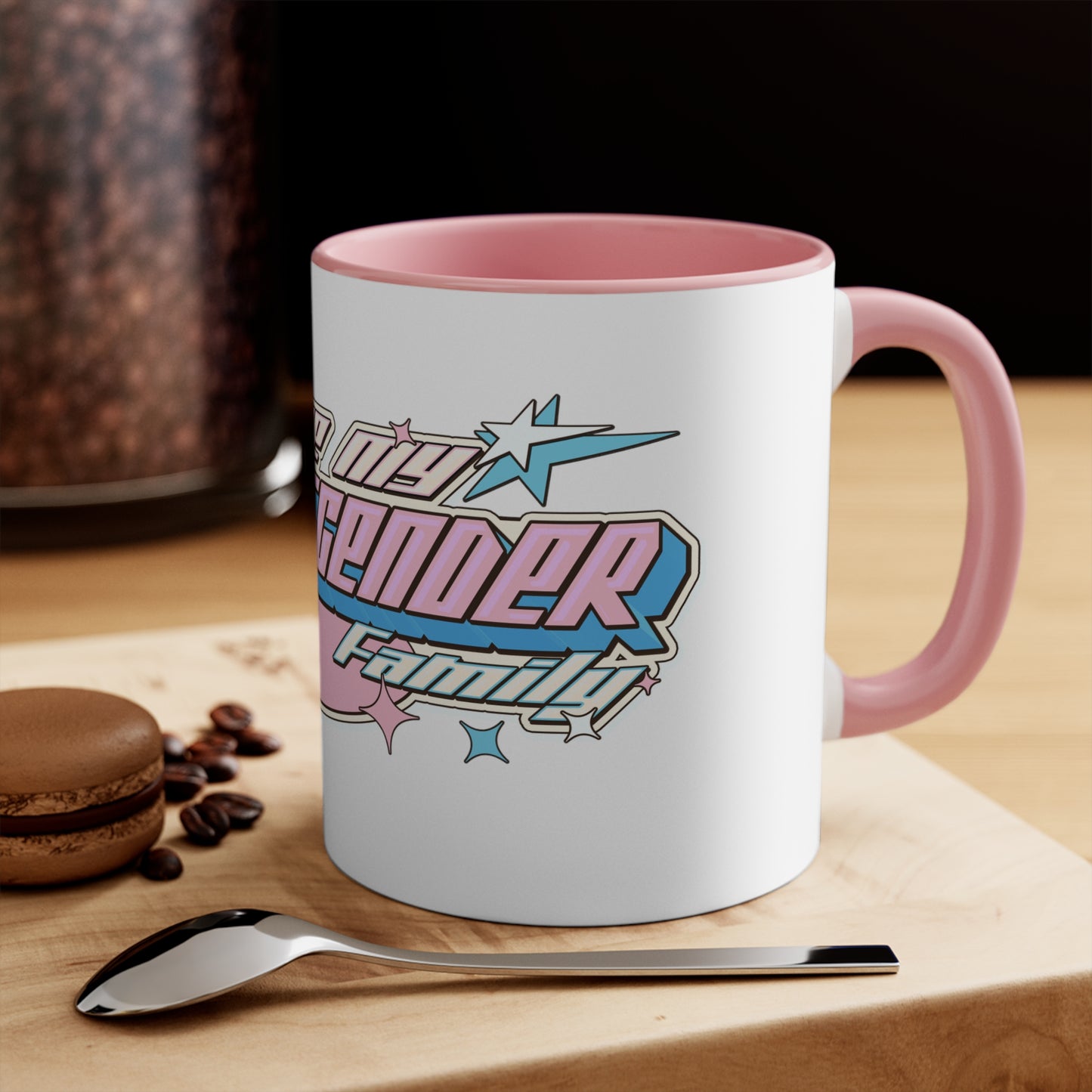 The "I Love My Transgender Family" original design accent mug by Printify features a white exterior with a vibrant, colorful interior. The retro-styled text reads "I Love My Transgender Family" in pink, blue, and cream colors accented by stars. This eye-catching design contrasts beautifully and evokes a nostalgic, vintage feel with its bold, decorative lettering.