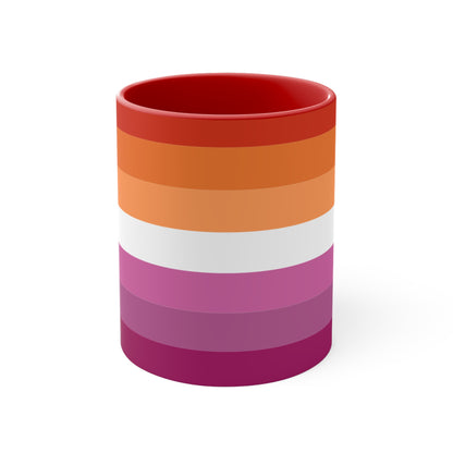 The Lesbian pride flag colorful accent mug by Printify features a vibrant design with horizontal stripes in varying shades of orange, pink, and purple. It has a red handle and colorful interior that create an eye-catching contrast against the plain white background.