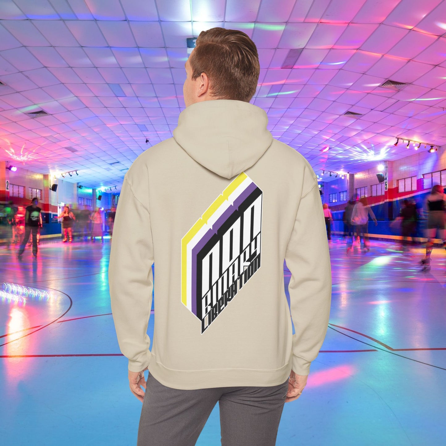 A person wearing the Non-Binary Liberation Hoodie - Australian Shipping by Printify, showcasing a vibrant geometric design on the back in nonbinary pride flag colours, stands in the middle of a roller skating rink. The rink is bathed in vibrant lights of various colors, with several people skating in the background.