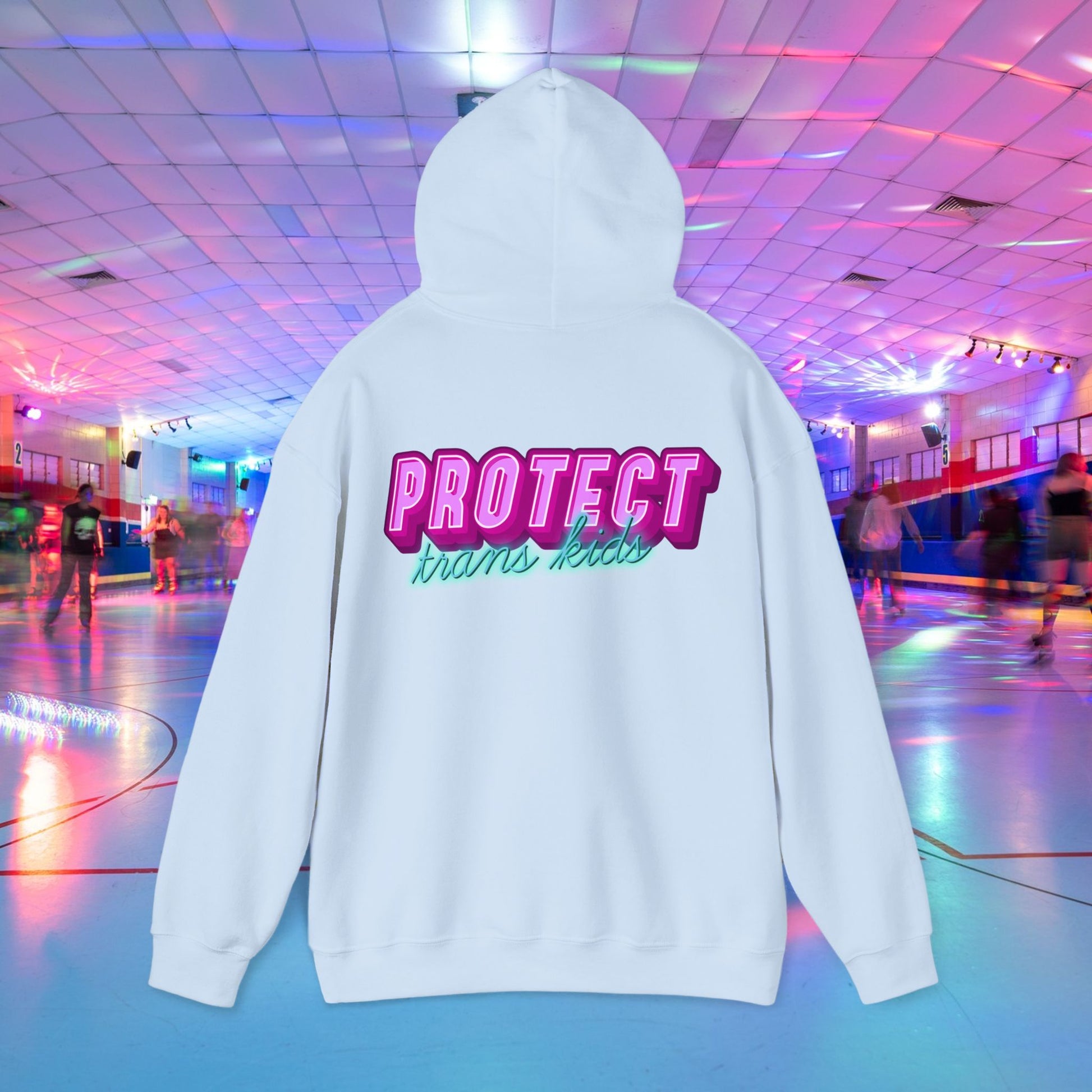 Displayed against a vibrant roller skating rink, the "Protect Trans Kids Hoodie - Australian Shipping" features bold pink and teal lettering on a white hoodie made from ethically grown cotton.