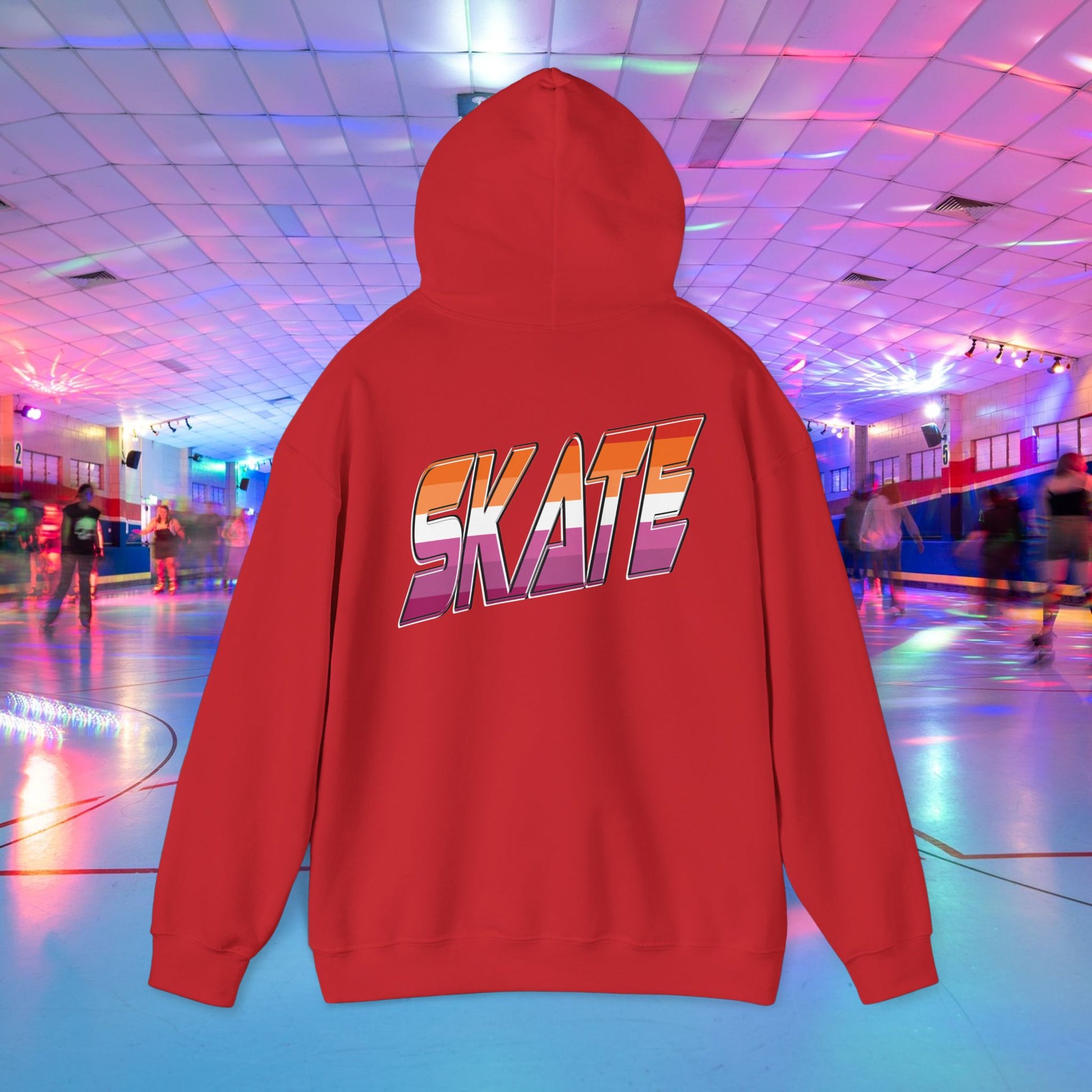 A black unisex "SKATE Lesbian Hoodie" by Printify, crafted from ethically grown US cotton, features the word "SKATE" in bold, colorful letters on the back. The hoodie is showcased in the foreground of a vibrant roller skating rink with neon lights and people skating in the background. Available for shipping to Australia.