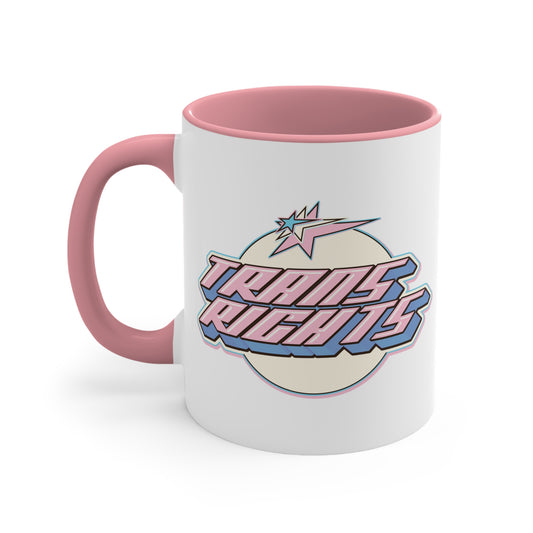 The Trans Rights colorful accent mug by Printify showcases a white coffee mug with a pink handle and vibrant interior, featuring the bold, retro-style text "TRANS RIGHTS" against a circular, off-white background. Above the text is a stylized star with dynamic lines that reflect the colors of the transgender pride flag, creating an energetic sense of movement.