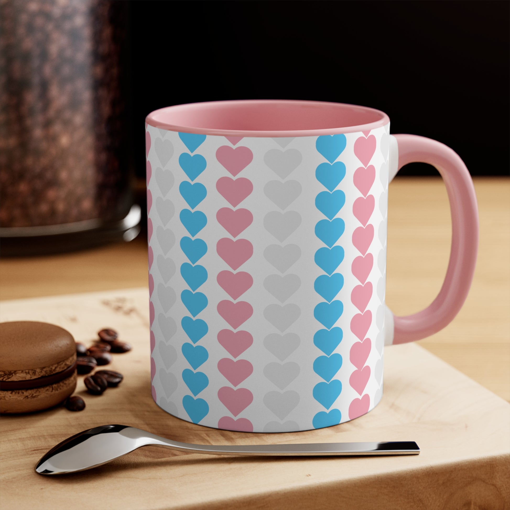 The Trans pride flag love hearts colourful accent mug by Printify features a white exterior adorned with vertical rows of pink, blue, and white hearts, reminiscent of the trans pride flag. Its cheerful and colorful appearance is enhanced by the pink handle and inner rim.