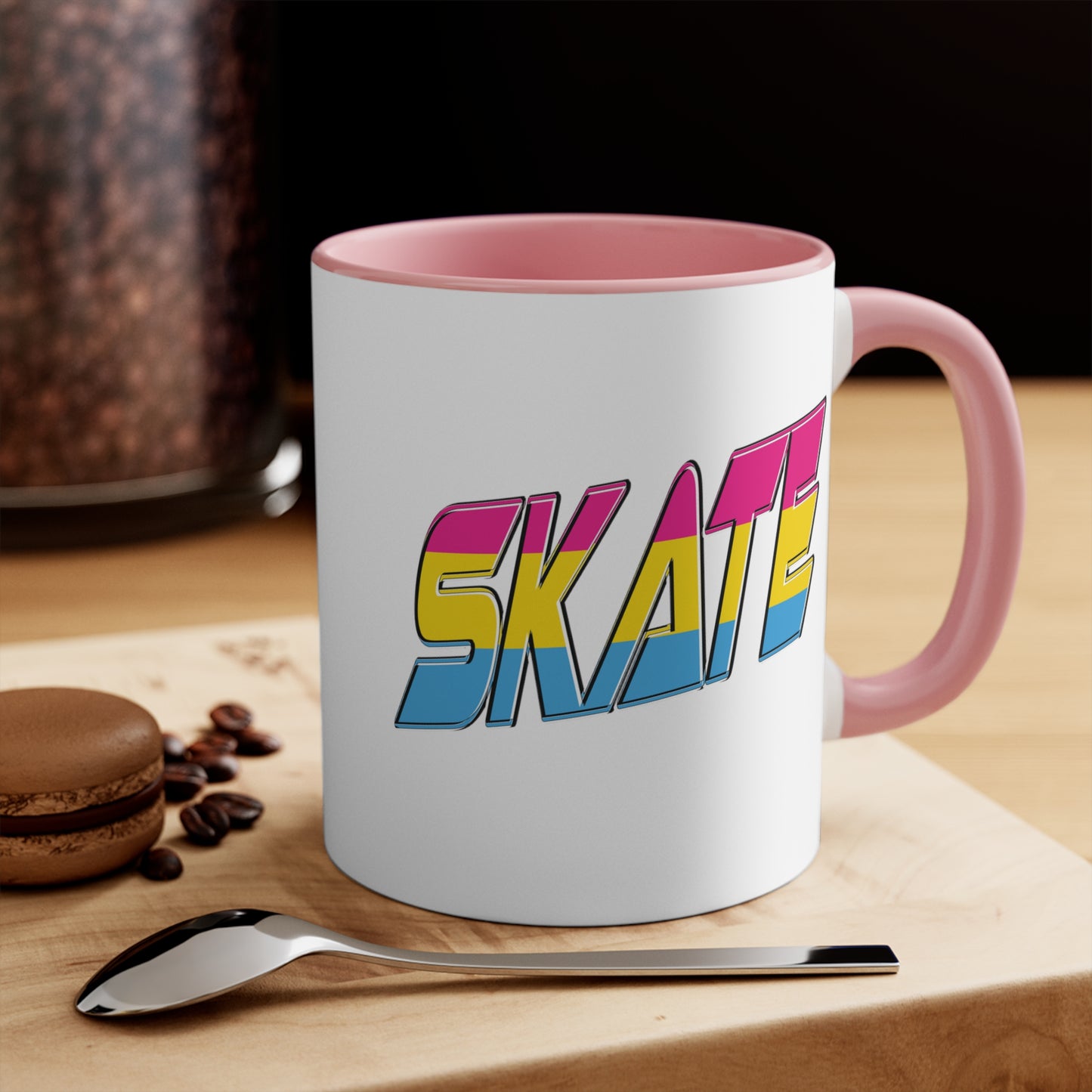 Introducing the "SKATE pansexual pride flag accent mug" by Printify—a white ceramic coffee mug highlighted with a black handle and interior. Adorned on the front are bold, colorful letters spelling "SKATE," featuring a gradient effect in pink, yellow, and blue that beautifully represents the pansexual pride flag.