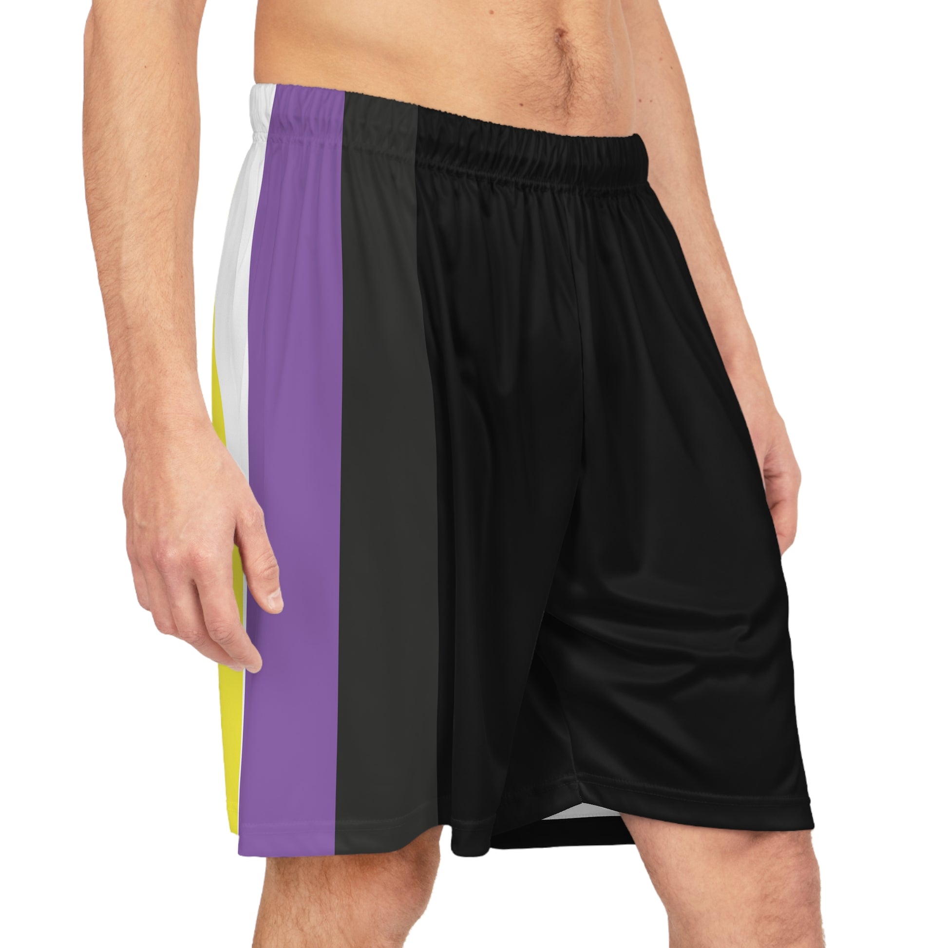 A person is standing wearing Non-Binary Pride Flag Basketball Shorts - Black from Printify, featuring an elastic waistband and side panels in vertical stripes of white, yellow, purple - thr nonbinary pride flag. The individual is shirtless, showing their midsection and a portion of their legs.