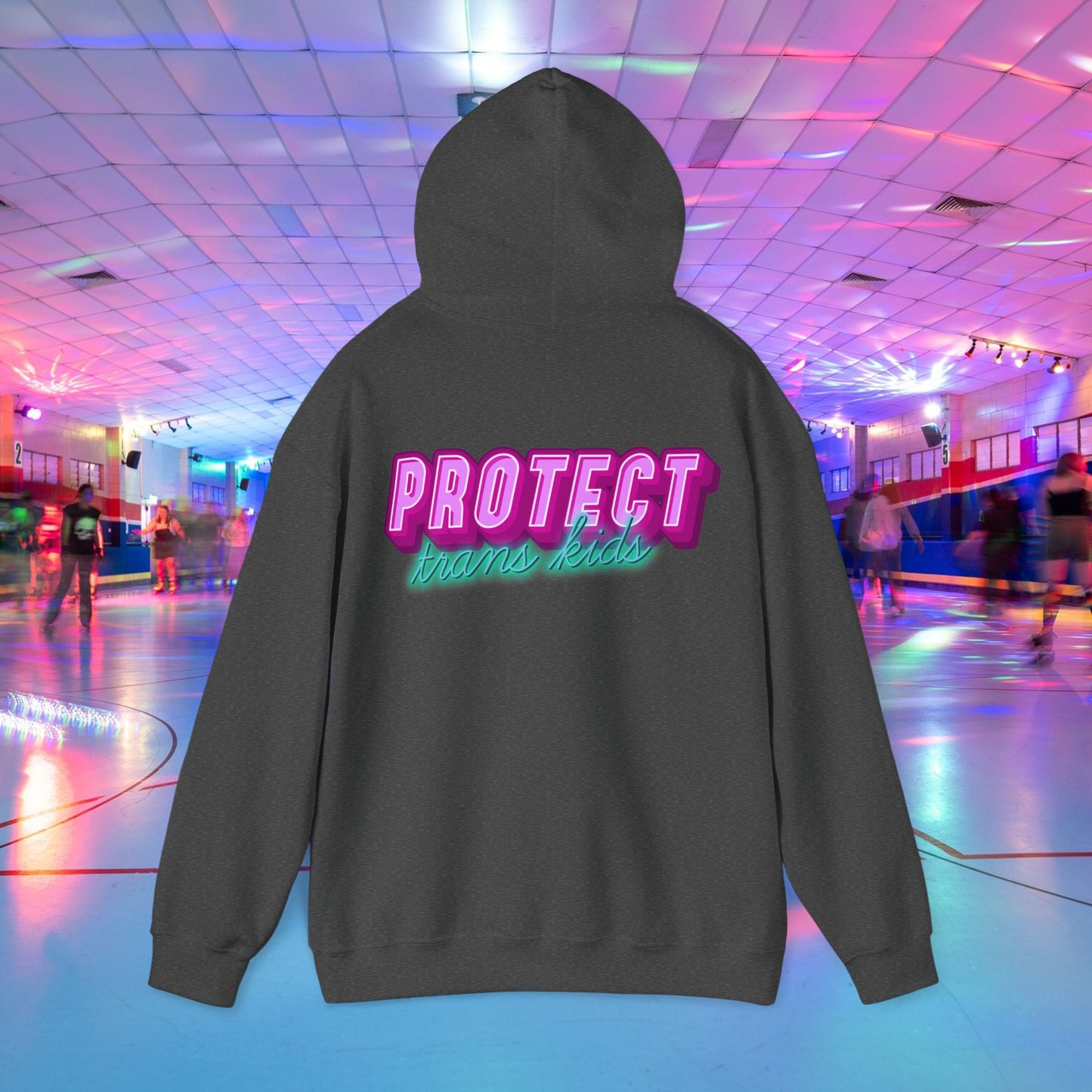 A unisex "Protect Trans Kids" hoodie, crafted from ethically grown cotton, is displayed. The bold pink and green lettering stands out against a vibrant background of a neon-lit roller skating rink with people in the distance.