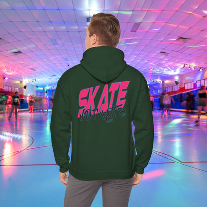 A person wearing a SKATE Not Hate Hoodie from Printify, characterized by its light pink color and high-quality construction, stands in a roller skating rink. The ethically-made unisex heavy blend hoodie, crafted from US-grown cotton, features the words "SKATE NOT HATE" printed on the back. The rink is adorned with colorful lights and has a shiny floor, with other skaters gliding in the background.