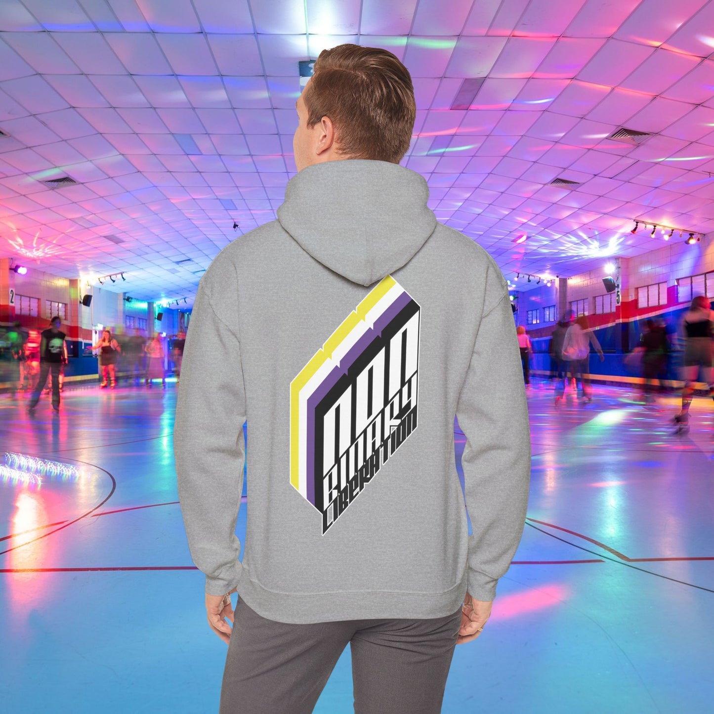 A person wearing the Non-Binary Liberation Hoodie - Australian Shipping by Printify, showcasing a vibrant geometric design on the back in nonbinary pride flag colours, stands in the middle of a roller skating rink. The rink is bathed in vibrant lights of various colors, with several people skating in the background.