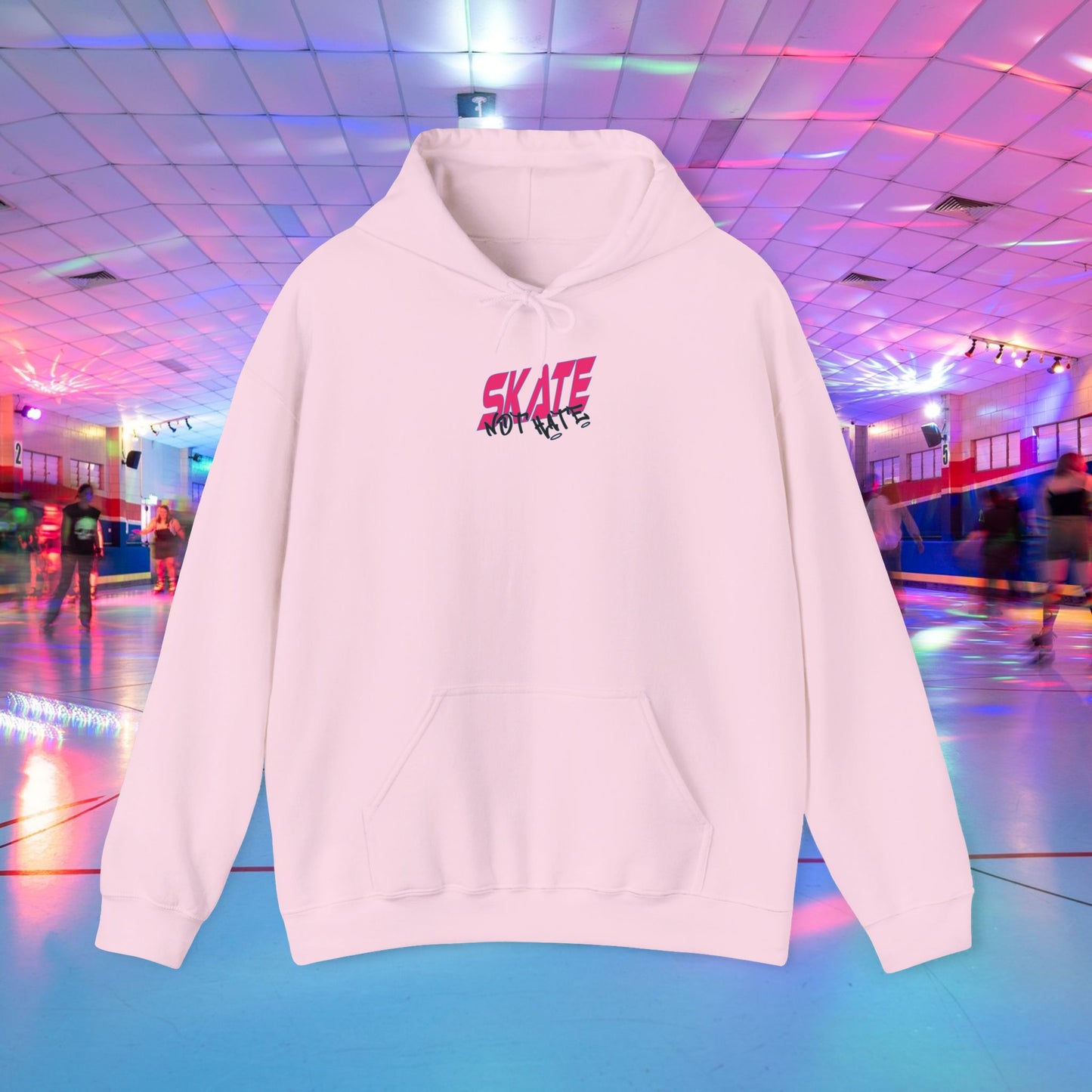 A person wearing a SKATE Not Hate Hoodie from Printify, characterized by its light pink color and high-quality construction, stands in a roller skating rink. The ethically-made unisex heavy blend hoodie, crafted from US-grown cotton, features the words "SKATE NOT HATE" printed on the back. The rink is adorned with colorful lights and has a shiny floor, with other skaters gliding in the background.