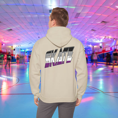 A person wearing a Printify SKATE Asexual Pride Hoodie, featuring the word "SKATE" printed on the back in gradient colors, stands in a brightly lit roller skating rink, observing the skaters. The rink is illuminated with colorful lights and exudes a lively atmosphere.