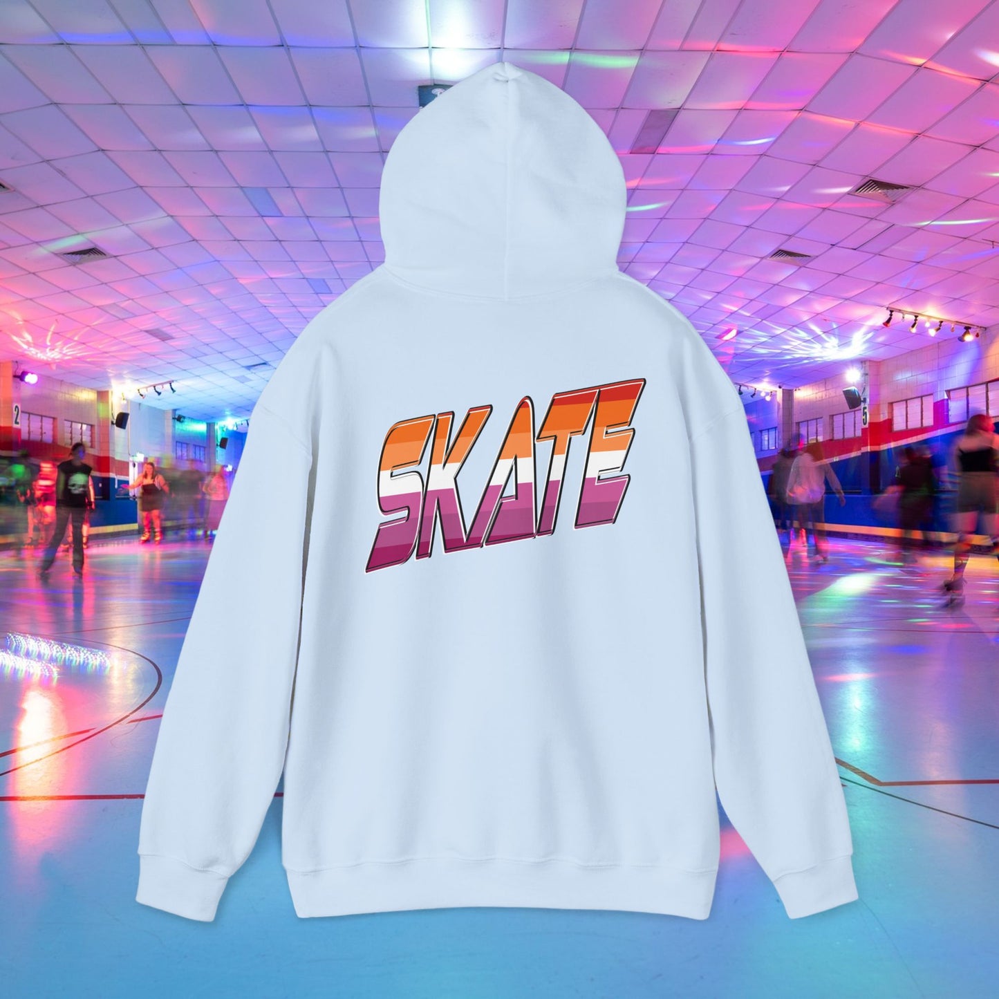 A black unisex "SKATE Lesbian Hoodie" by Printify, crafted from ethically grown US cotton, features the word "SKATE" in bold, colorful letters on the back. The hoodie is showcased in the foreground of a vibrant roller skating rink with neon lights and people skating in the background. Available for shipping to Australia.