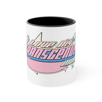 The "I Love My Transgender Mum" original design accent mug by Printify is a white ceramic mug with a vibrant pink interior. It features the stylized word "Transcend," adorned with stars and gradient shades of pink, blue, and purple that represent the colors of the transgender pride flag.