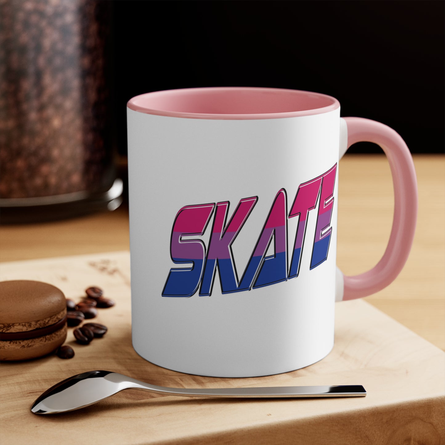 The Printify SKATE bisexual pride flag accent mug features a white base with a blue handle and vibrant interior. It proudly displays the word "SKATE" in bold, stylized gradient lettering, transitioning from pink at the top to blue at the bottom, creating an eye-catching contrast that evokes a sense of movement and energy.