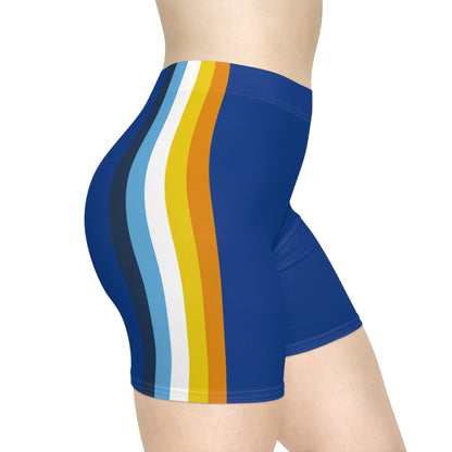 A person wearing Printify's Aroace Pride Flag Bike Shorts, which are high-waisted blue athletic shorts featuring vertical stripes in dark blue, light blue, white, yellow, and orange down the side. The photo captures the lower torso and upper thighs from a side view.