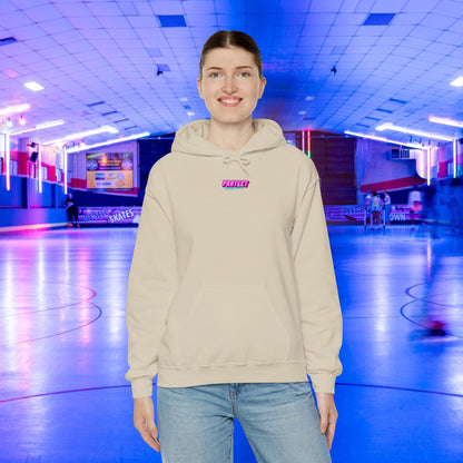 Wearing a Protect Trans Kids Hoodie - Australian Shipping and jeans, a person stands smiling in a neon-lit skating rink. The scene is bathed in blue and pink lights, with blurred figures gliding on the skating paths in the background.