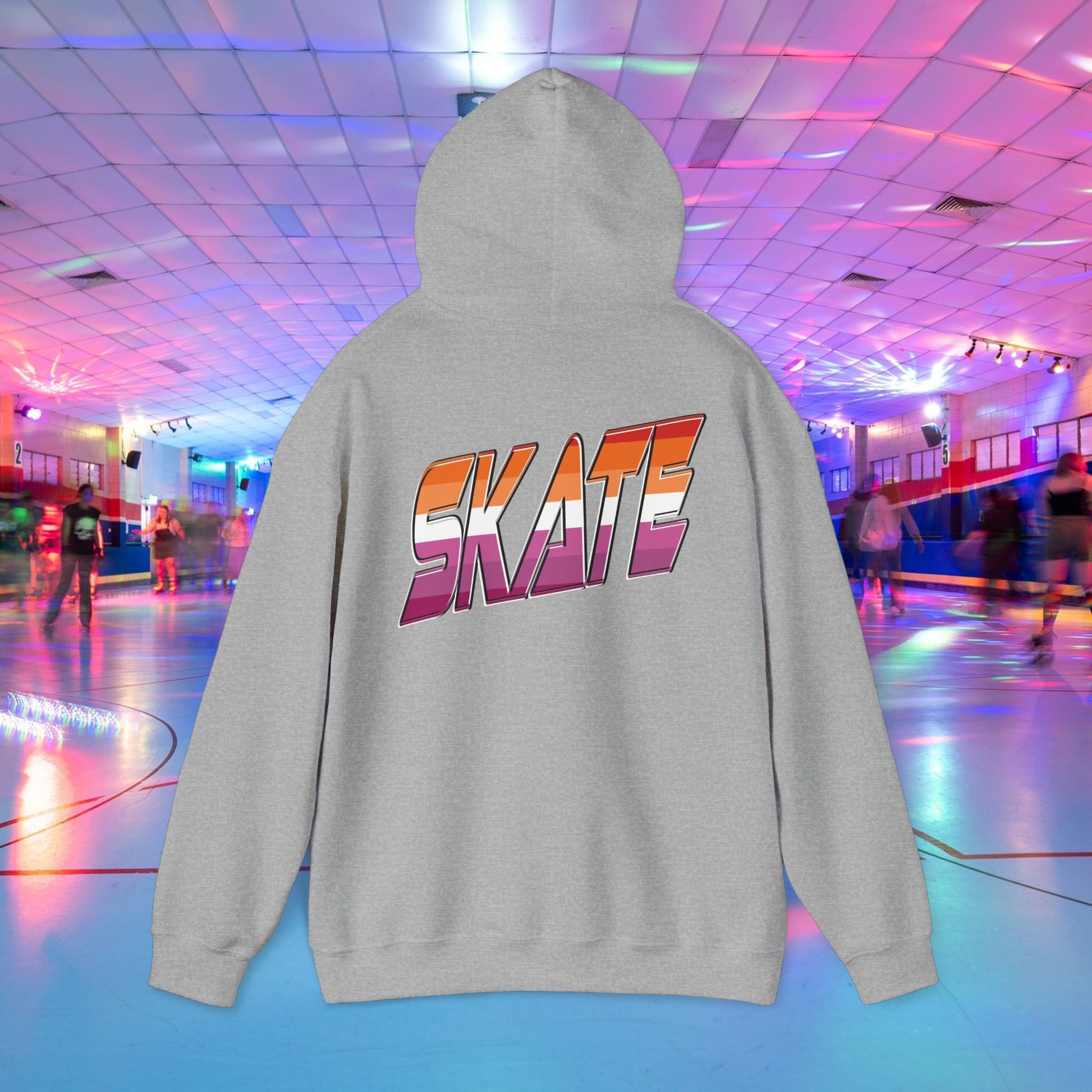 A black unisex "SKATE Lesbian Hoodie" by Printify, crafted from ethically grown US cotton, features the word "SKATE" in bold, colorful letters on the back. The hoodie is showcased in the foreground of a vibrant roller skating rink with neon lights and people skating in the background. Available for shipping to Australia.