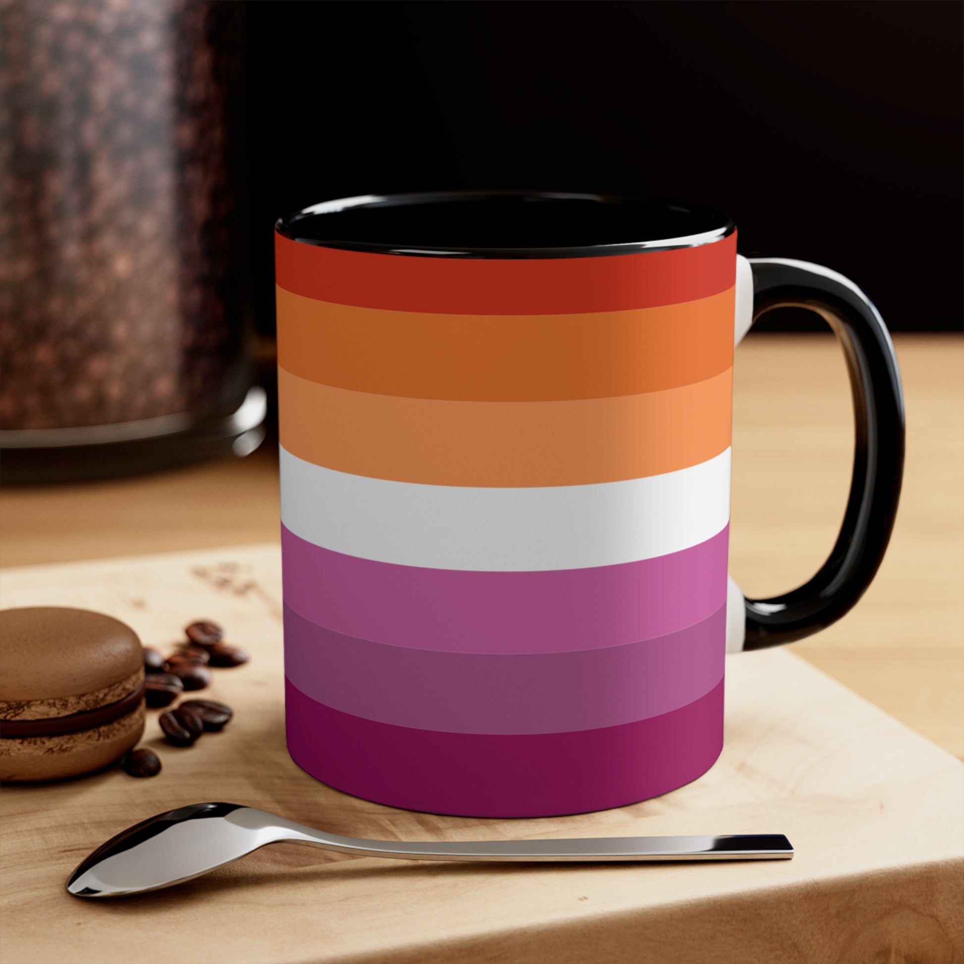 The Lesbian pride flag colorful accent mug by Printify features a vibrant design with horizontal stripes in varying shades of orange, pink, and purple. It has a red handle and colorful interior that create an eye-catching contrast against the plain white background.