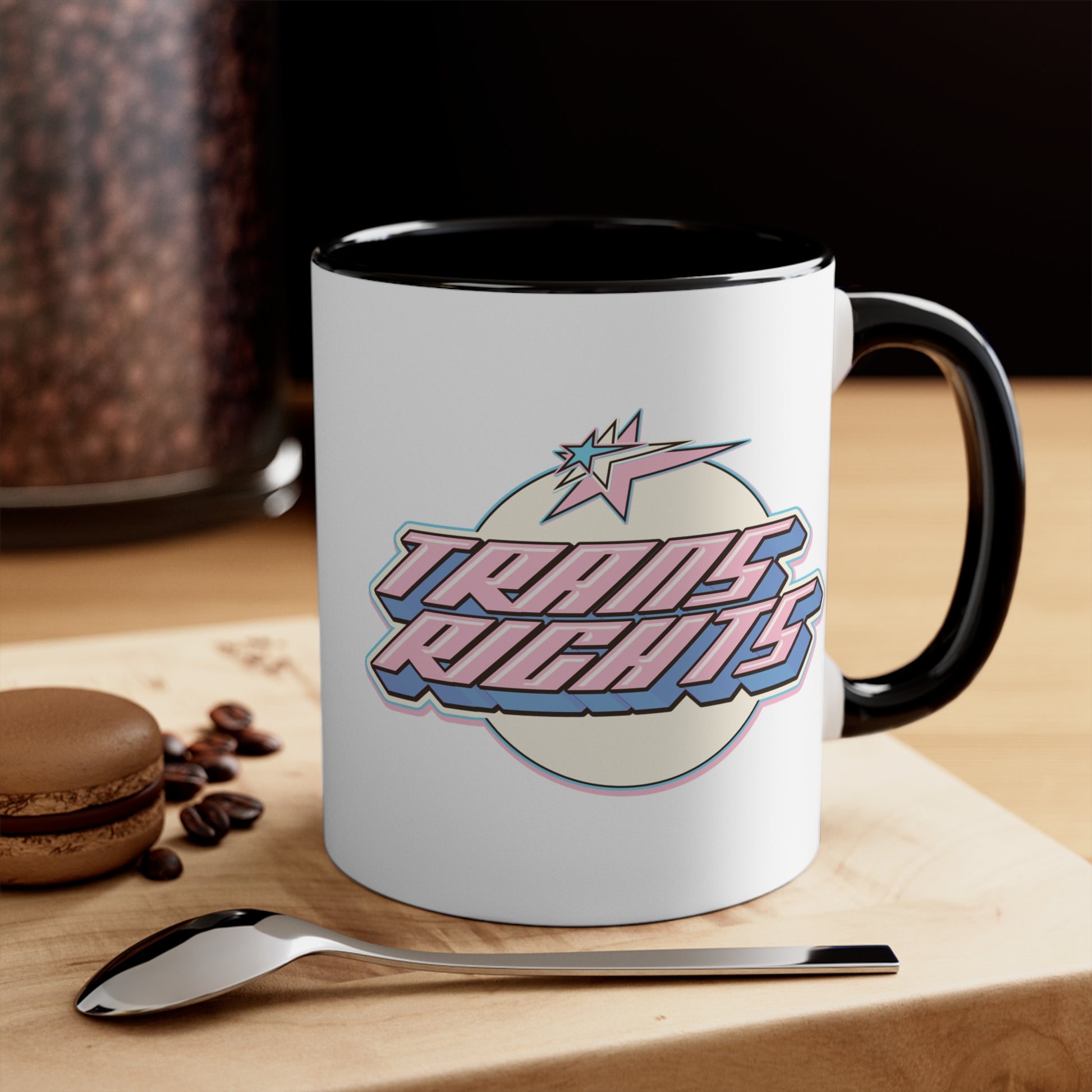 The Trans Rights colorful accent mug by Printify showcases a white coffee mug with a pink handle and vibrant interior, featuring the bold, retro-style text "TRANS RIGHTS" against a circular, off-white background. Above the text is a stylized star with dynamic lines that reflect the colors of the transgender pride flag, creating an energetic sense of movement.