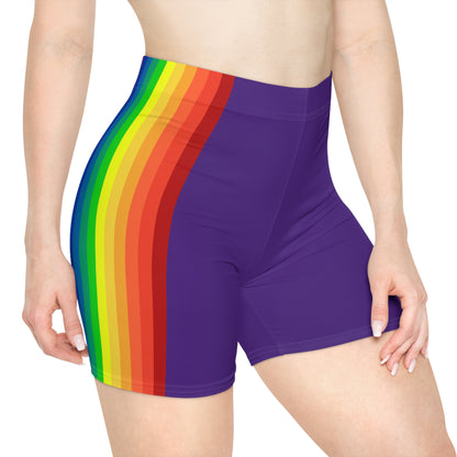 A person is wearing Rainbow and Purple Bike Shorts, which feature a bold, vertical rainbow pride flag stripe pattern on the side in red, orange, yellow, green, blue, and purple. These form-fitting shorts are made from moisture-wicking polyester spandex and have a neutral white background.