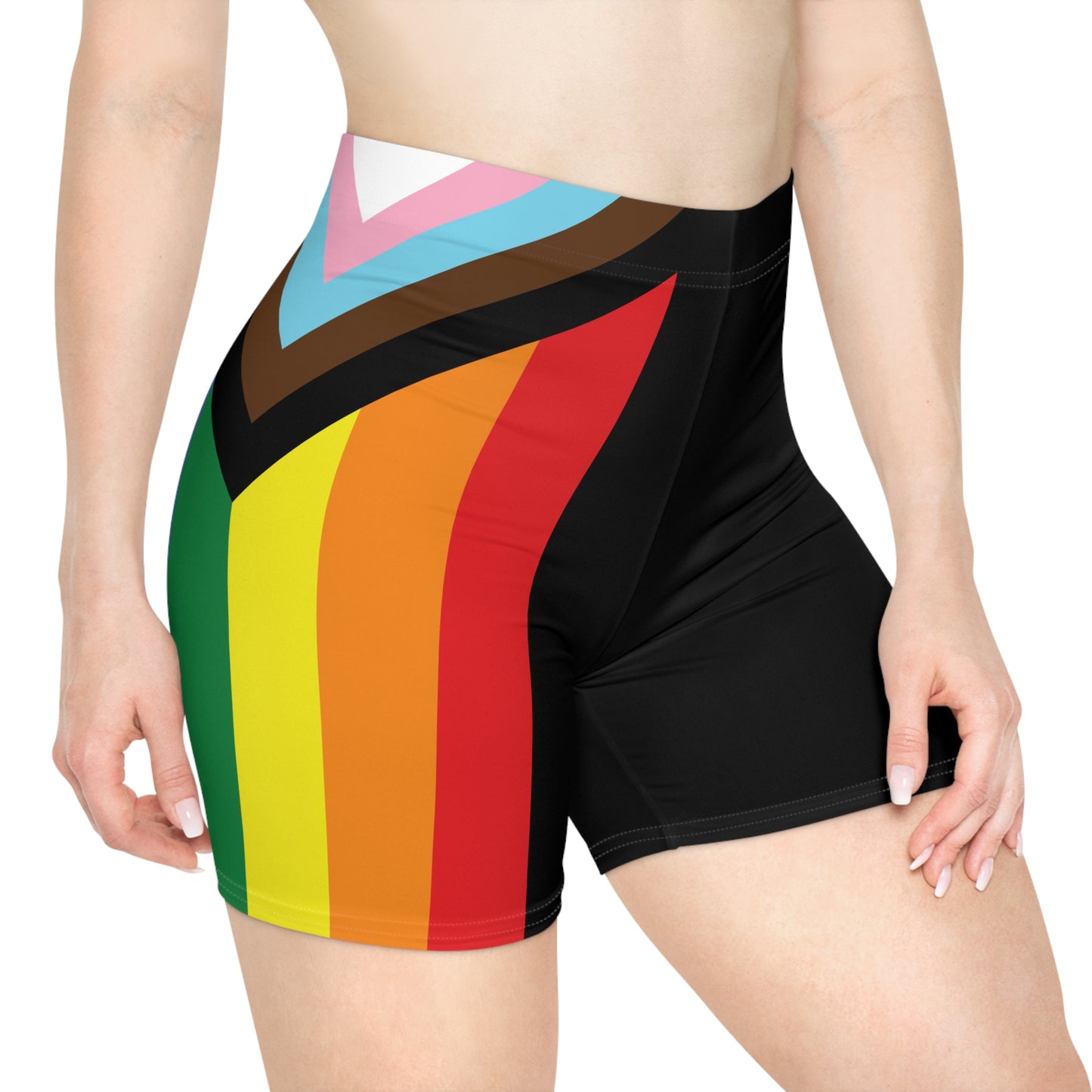 A person is wearing Progress Pride Bike Shorts by Printify, which feature a colorful design with a rainbow pride flag incorporating stripes for people of color and the transgender community. These moisture-wicking shorts fit closely to the body.